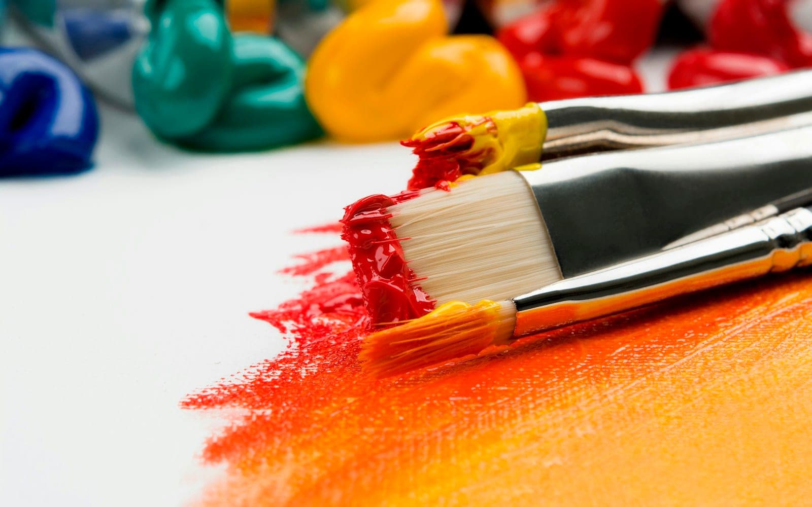 three silver paint brushes on white textile