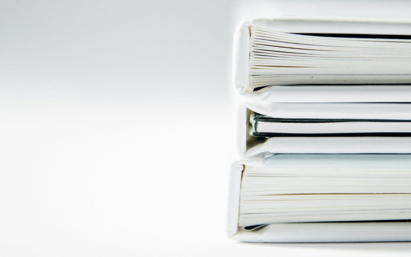 A stack of thick folders on a white surface