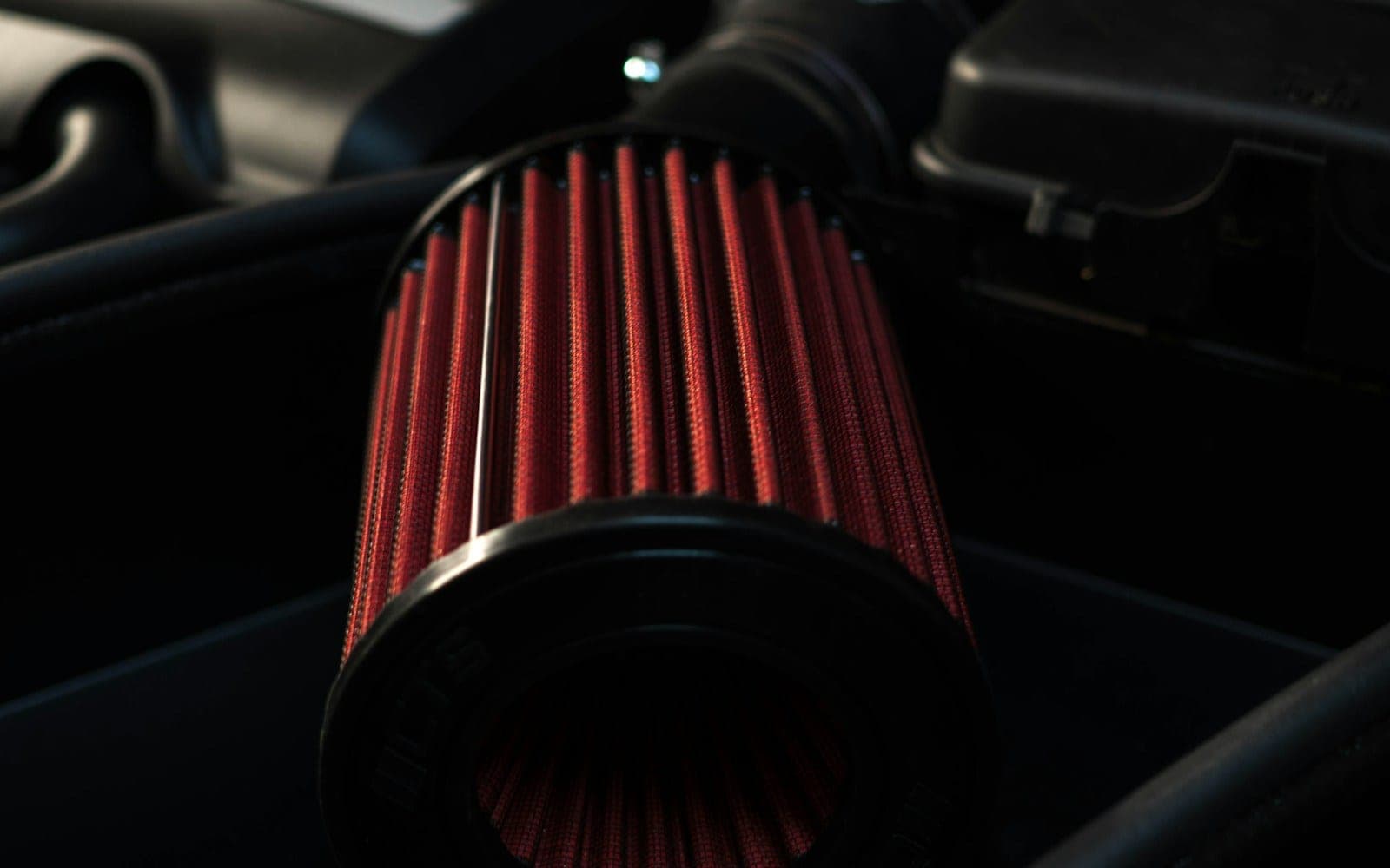Pleated red vehicle air filter fitted inside an engine bay.