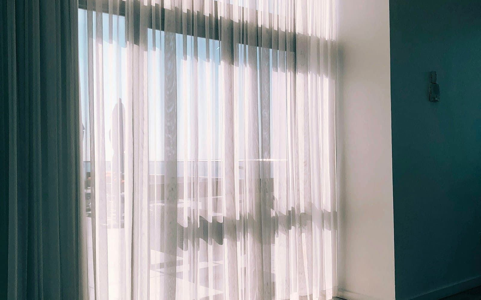 Sheer white curtains and heavier blue curtain panels beside a window.