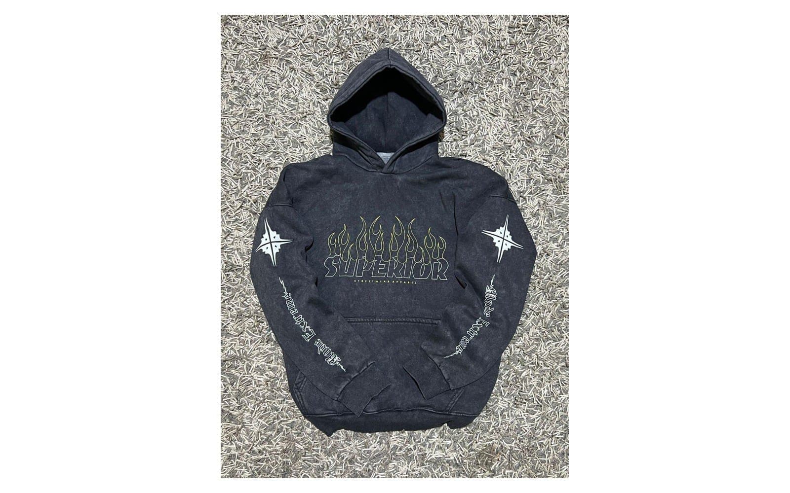 Dark hooded sweatshirt laid flat on a textured surface.