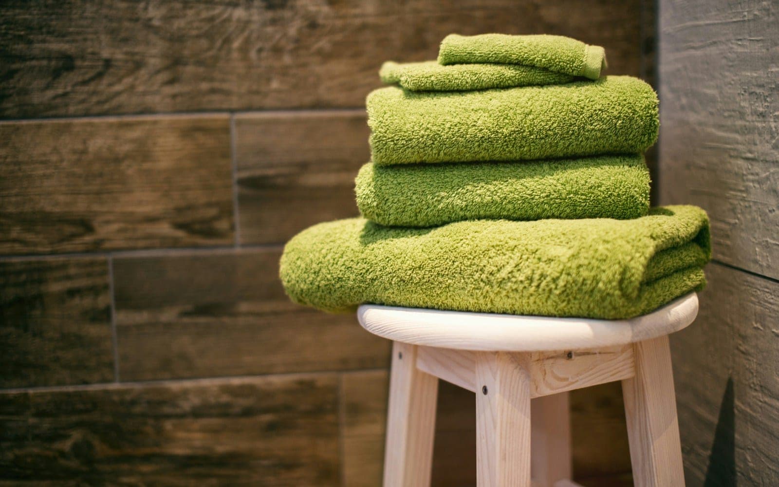Stack of folded green bath towels in different sizes.