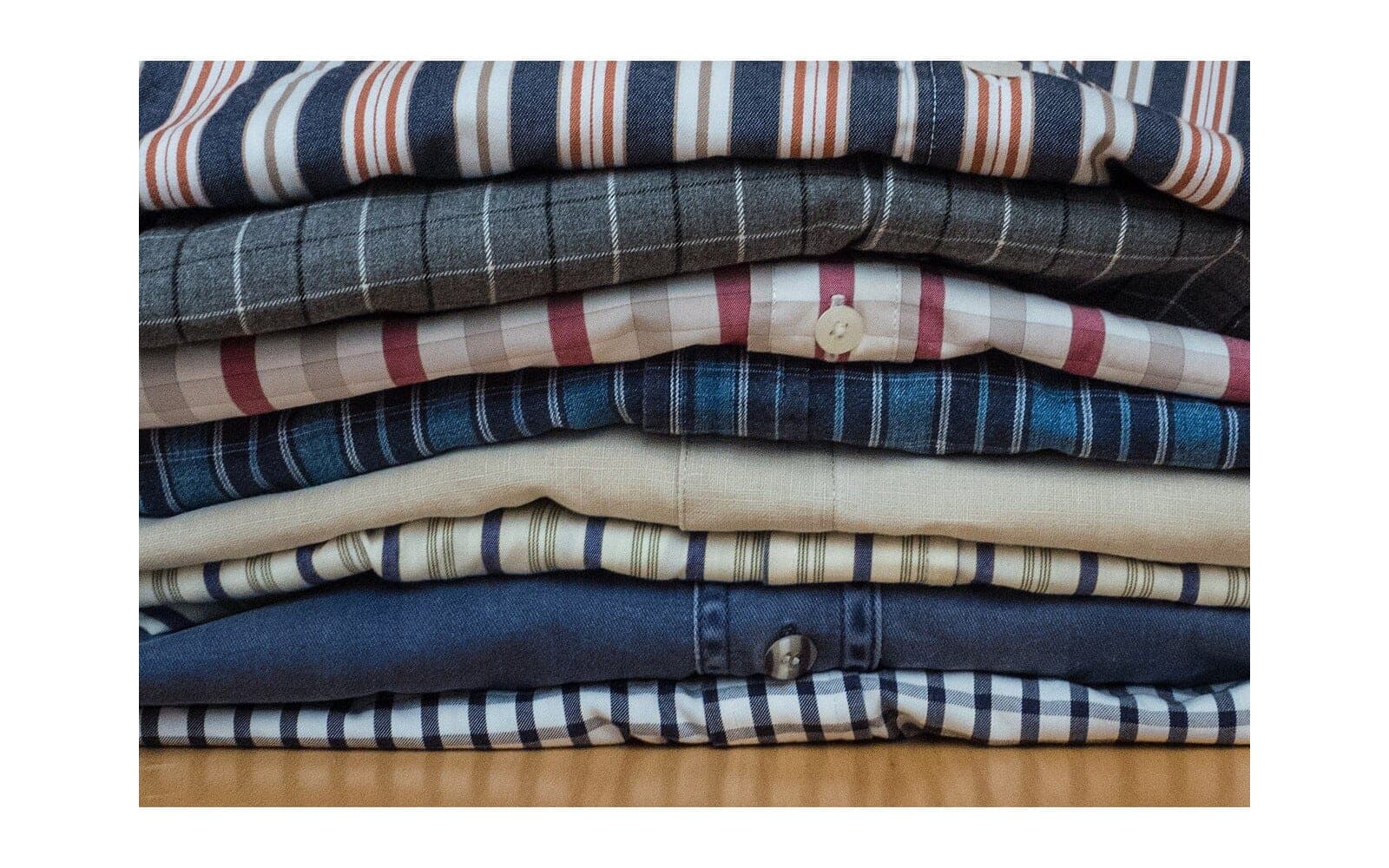 Stack of folded casual shirts in plain and checked fabrics.