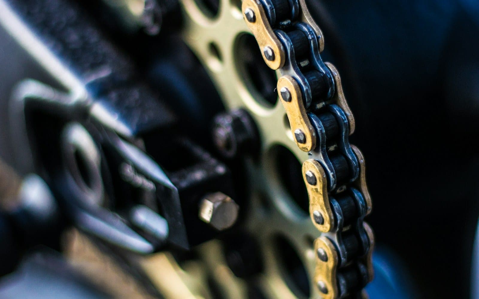 Close-up of a motorcycle drive chain wrapped around a rear sprocket.
