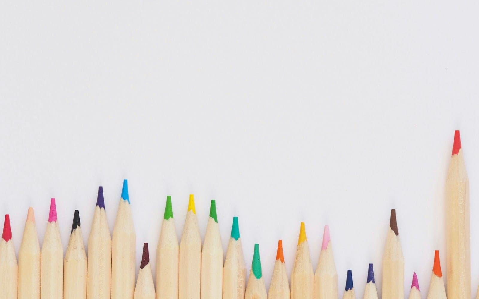 Coloured pencils arranged in a row on a light background.