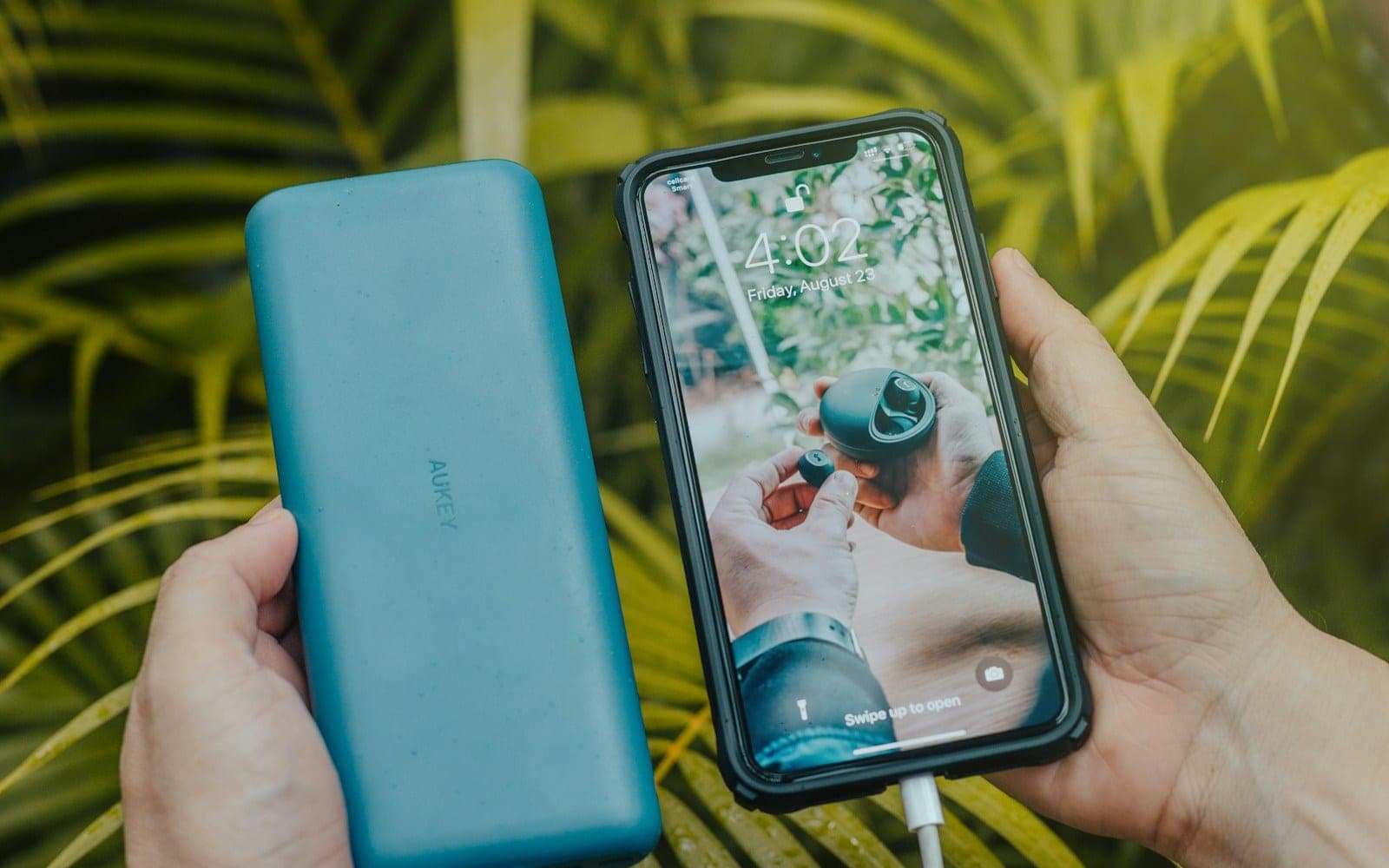 Portable power bank connected to a smartphone with a charging cable.