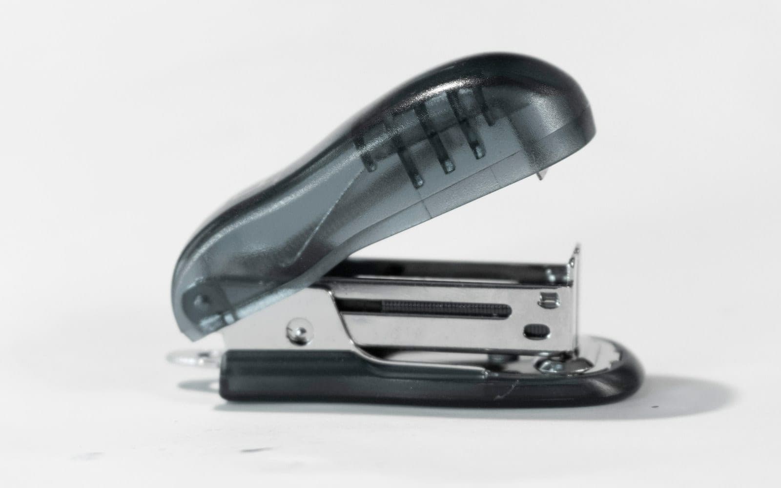 Open desktop stapler on a light surface.
