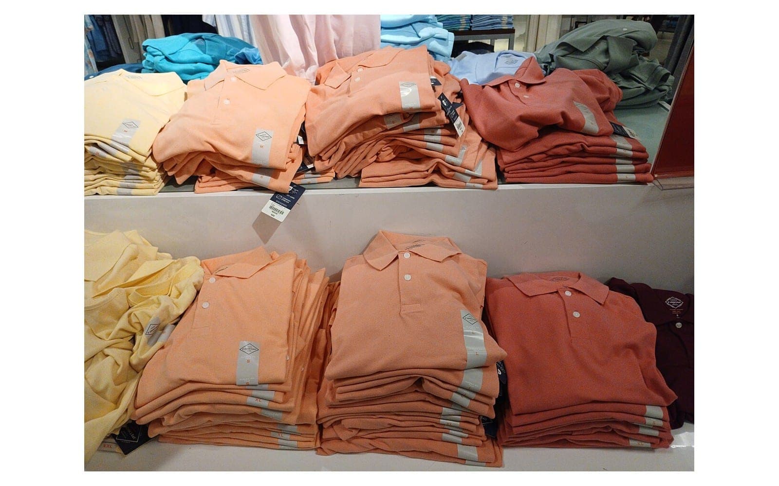 Folded polo shirts in several colours displayed on retail shelves.